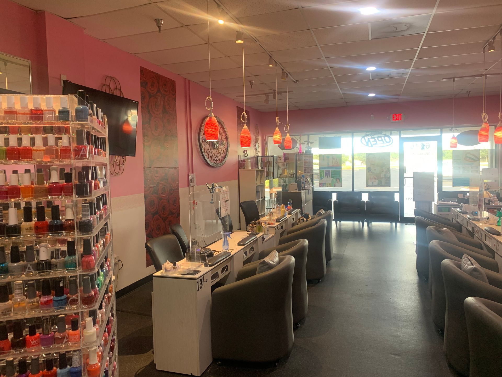 Interior of a nail salon with nail polish racks, chairs, and nail stations.