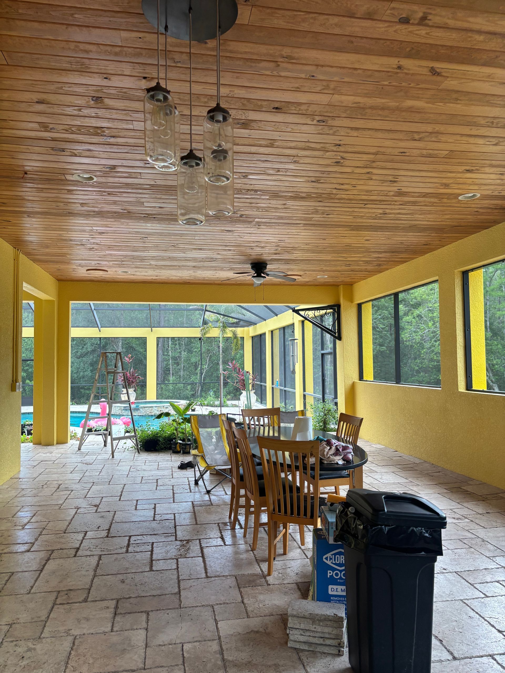 Covered patio with a dining table and chairs, yellow walls, and view of pool area.