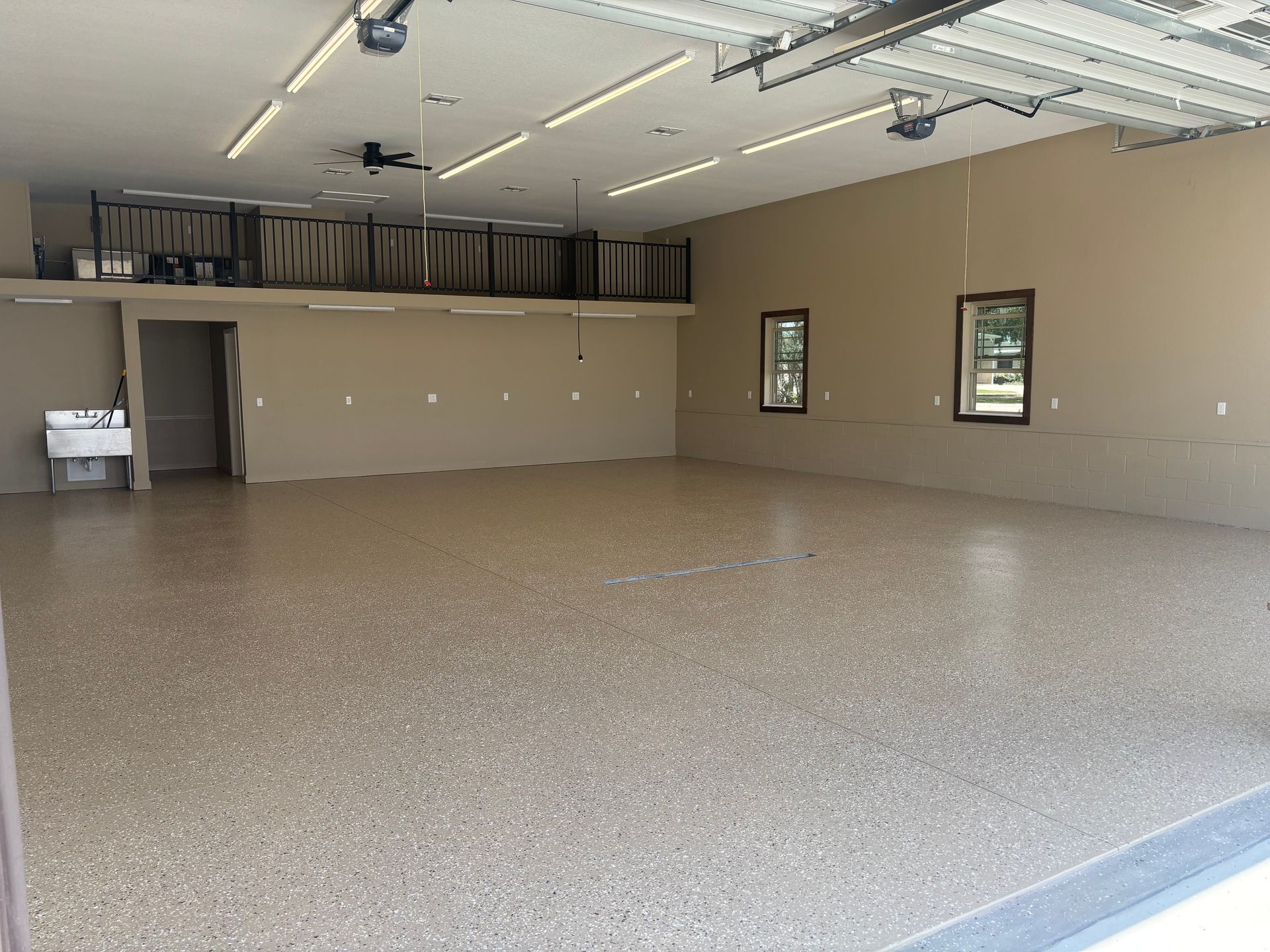 Spacious, empty garage with a polished concrete floor, neutral walls, and a loft area.