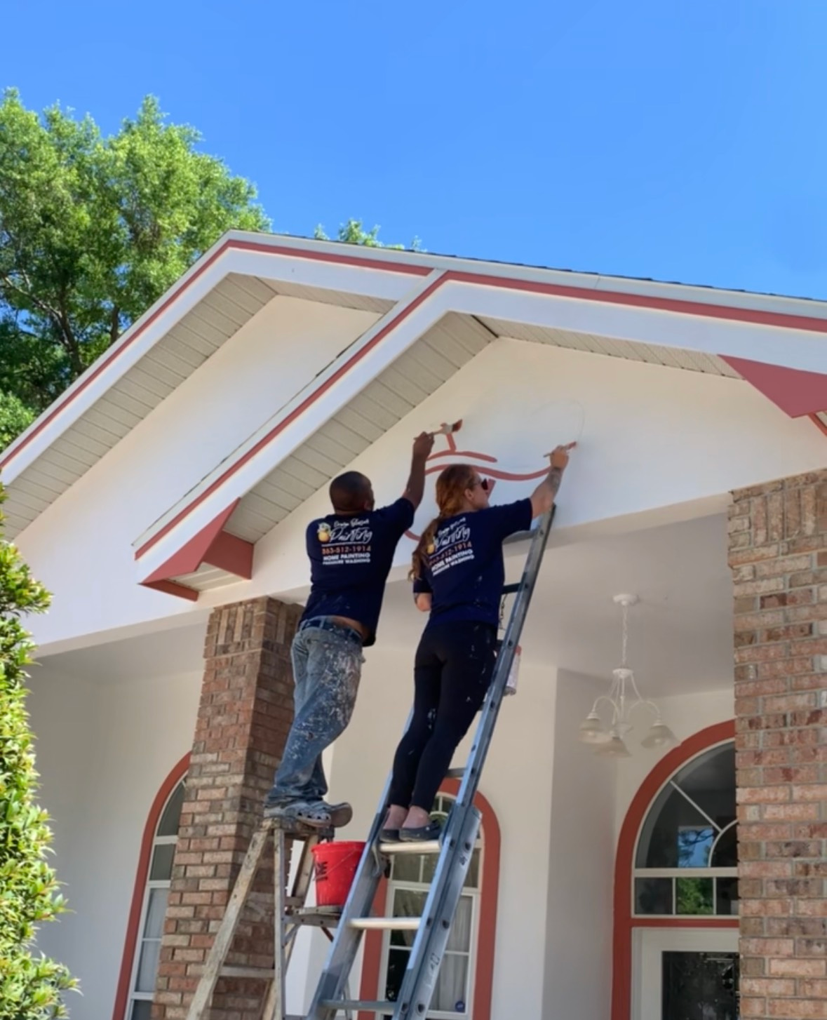 A man and a woman are painting the side of a house