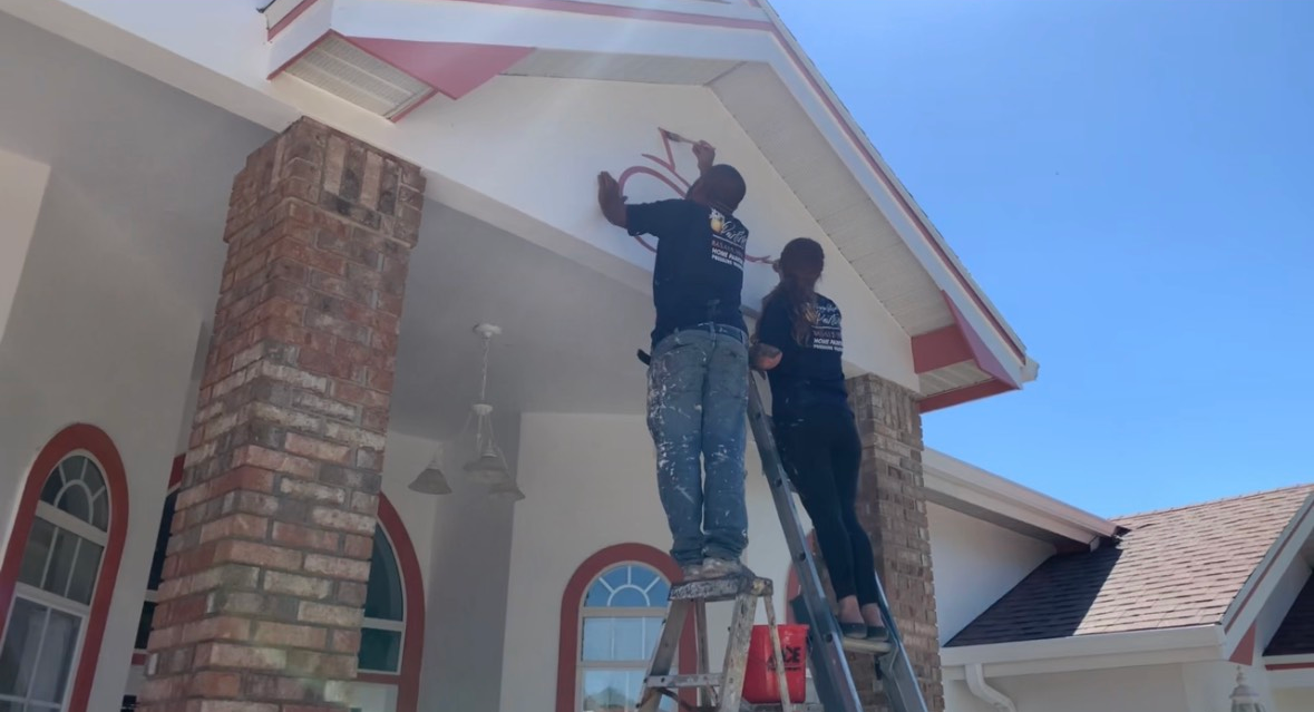 Two men are painting the roof of a house.