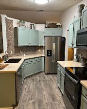 Kitchen with light-blue cabinets, stainless steel appliances, and wood-look flooring.