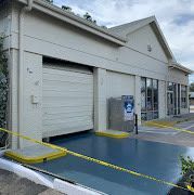 Exterior of a building with a garage door, blue platform, and yellow caution tape.