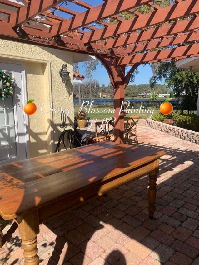 Outdoor patio with wooden table, pergola, and water view.