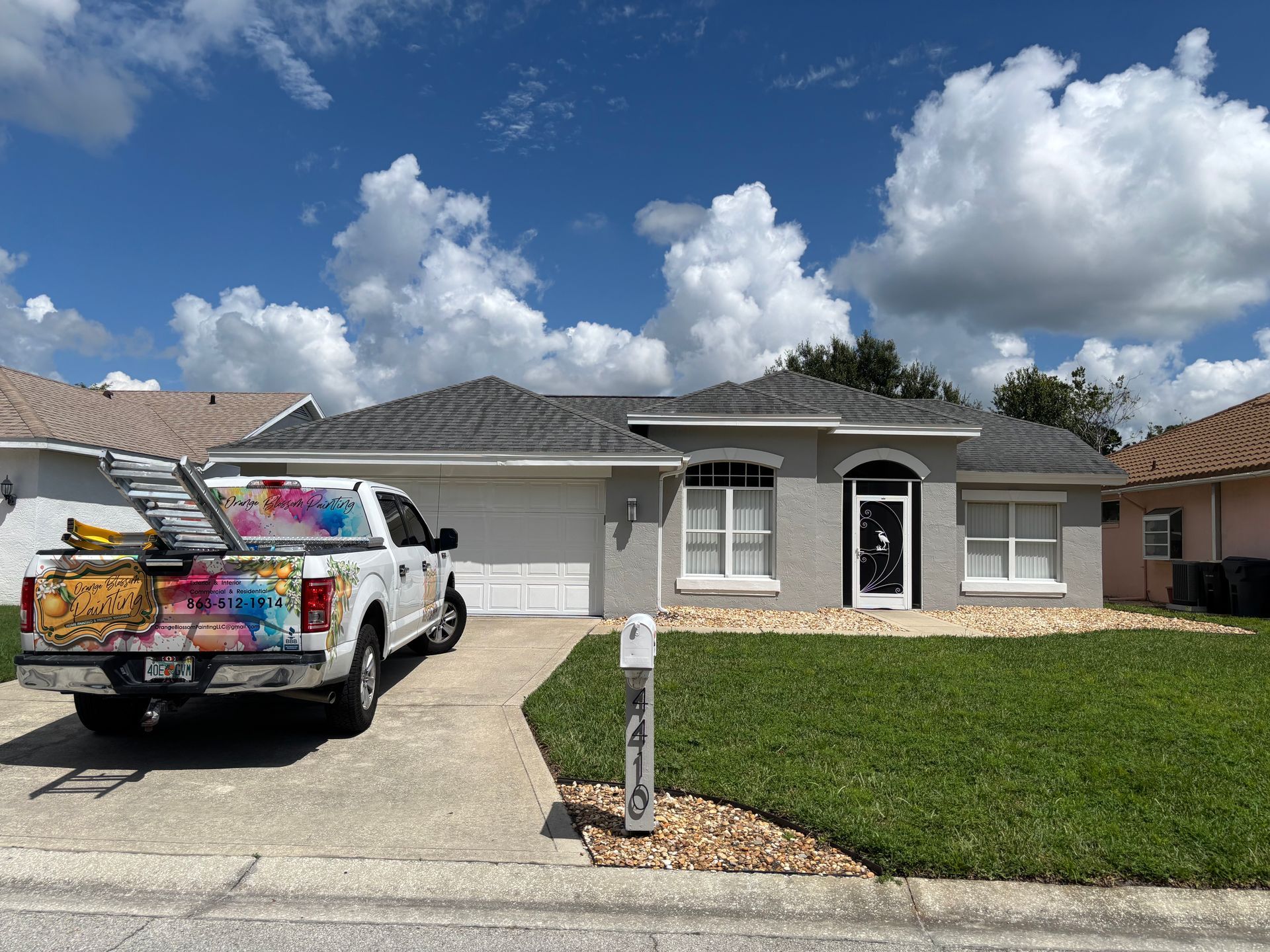 A gray house with a white truck parked in the driveway on a sunny day.