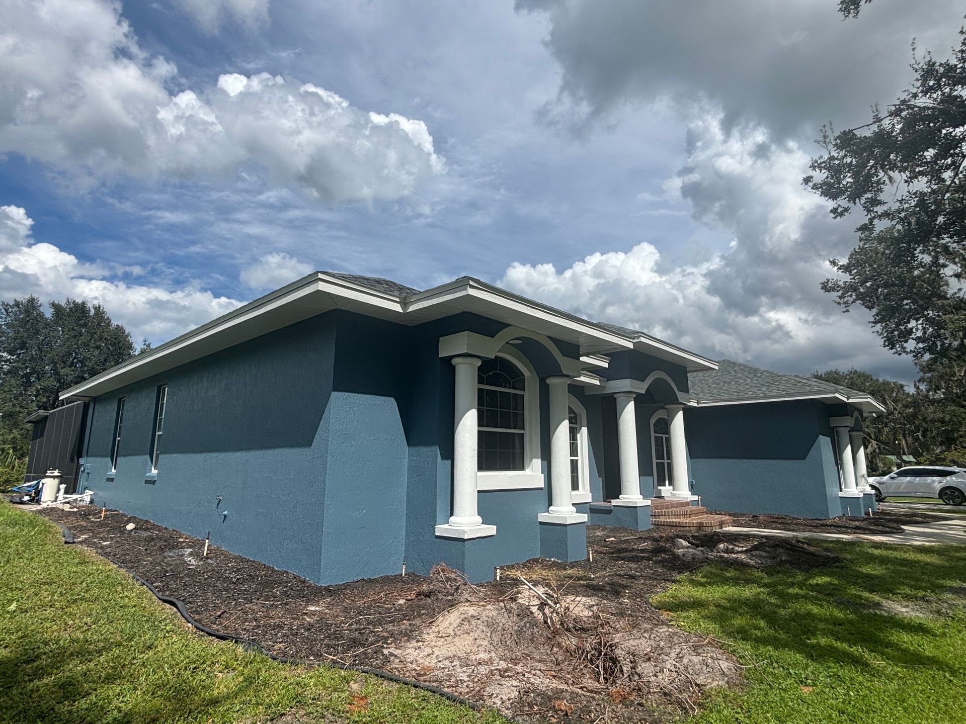 Blue and white house with columns under a cloudy sky.