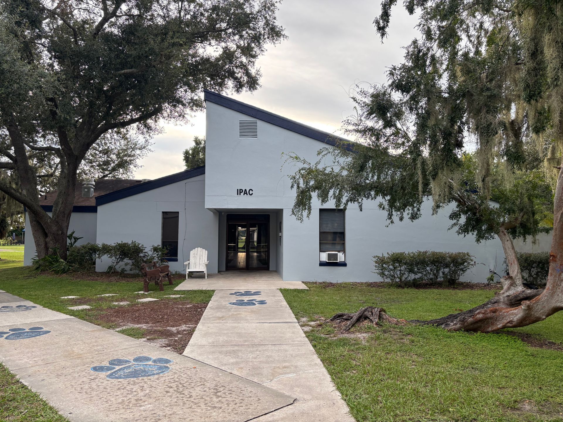 Blue building with angled roof, trees, and walkway. Number 