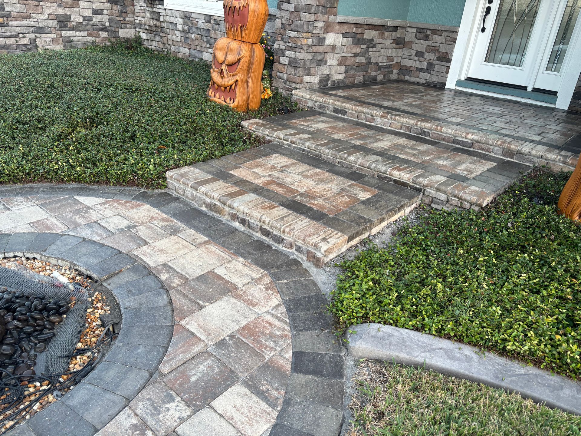 Brick walkway leading to steps and entrance with manicured landscaping.