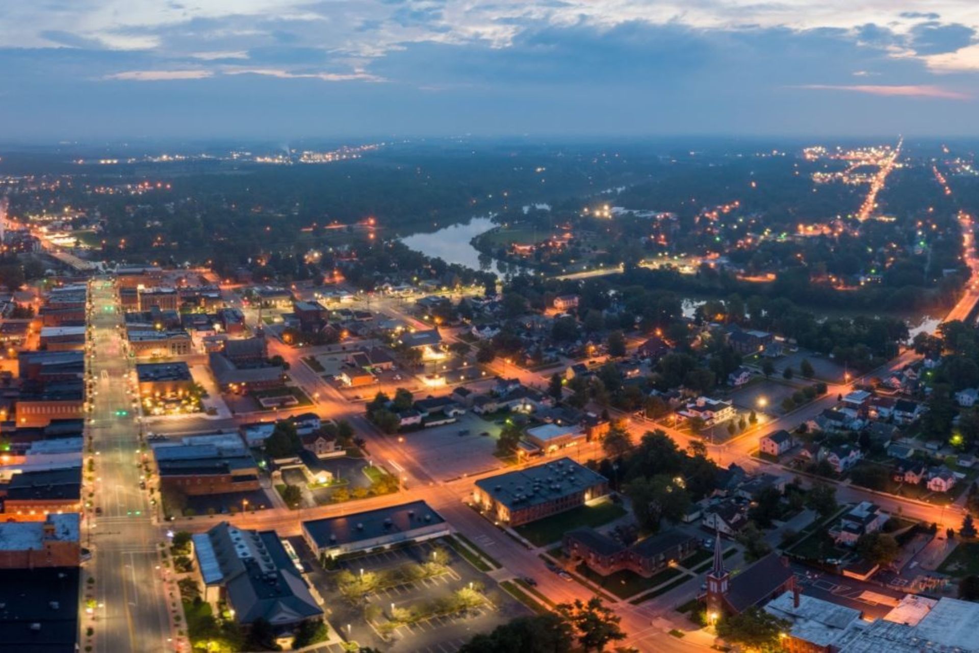 An aerial view of a city at night with a lake in the background.