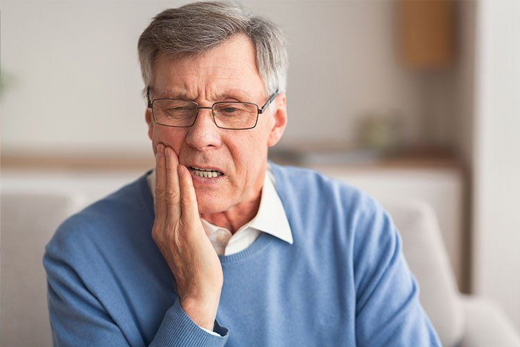 elderly patient holding cheek in Salem MA