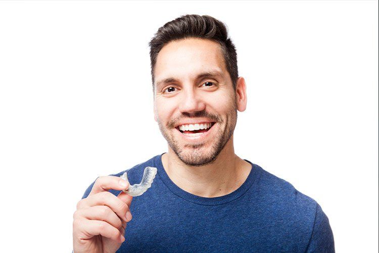 invisalign patient smiling holding clear tray