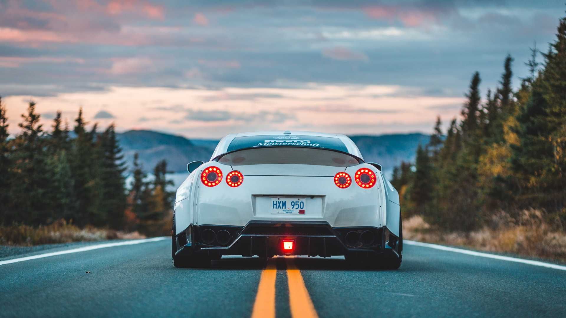 a luxury car driving away down the center of the road
