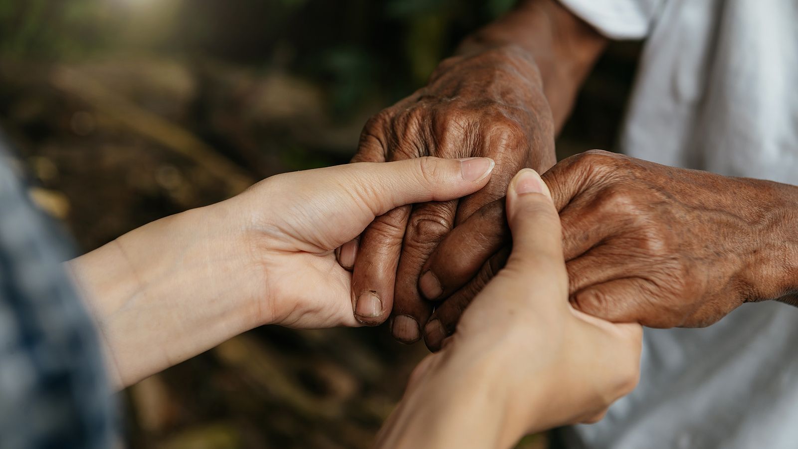A woman is holding the hands of an older man.