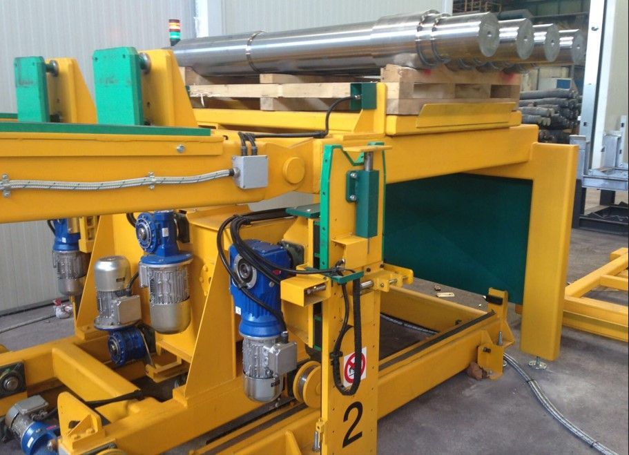 Macchina industriale gialla con oggetto metallico cilindrico su un pallet.