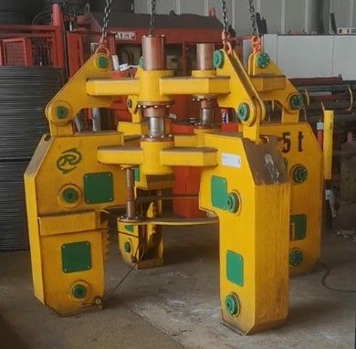 Pinza di sollevamento industriale gialla sospesa tramite catene, progettata per sollevare oggetti cilindrici.