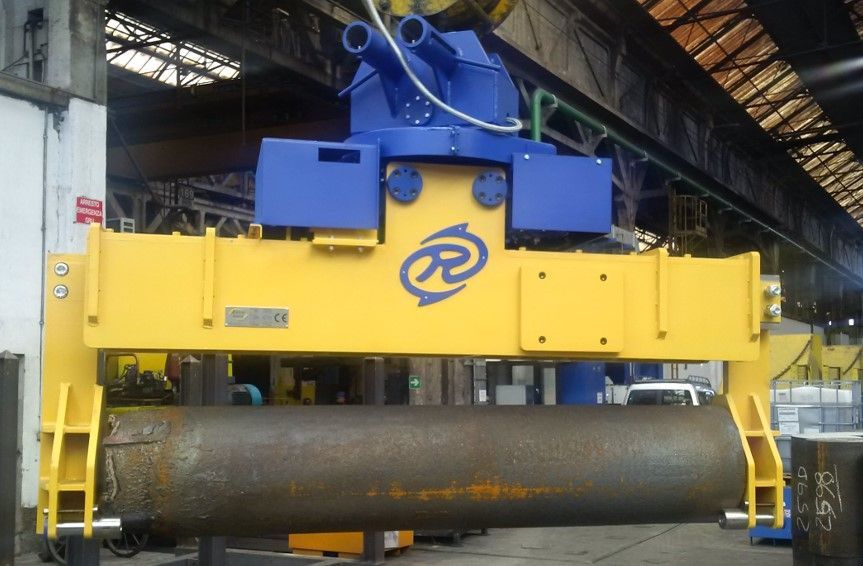 Un sollevatore industriale giallo e blu che regge un grande tubo d'acciaio in un ambiente industriale.