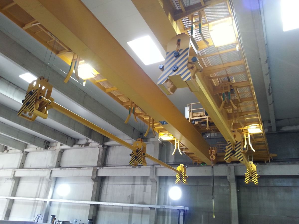 Sistema di gru a ponte gialla all'interno di un grande edificio industriale.