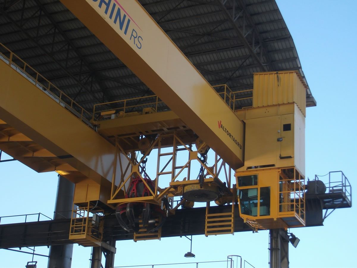 Gru a ponte gialla in ambiente industriale, con cabina di controllo.