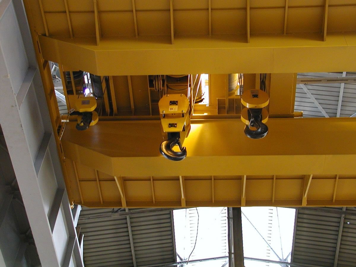 Gru a ponte gialla con tre ganci in un ambiente industriale.