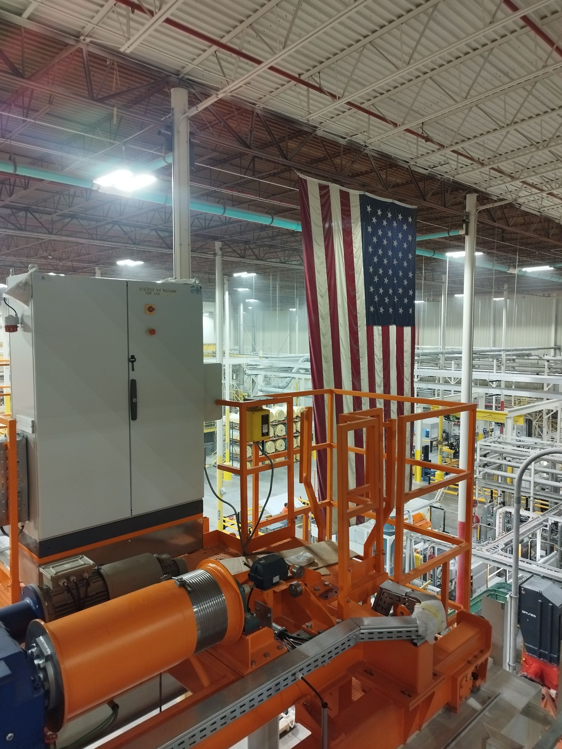 La bandiera americana è appesa sopra i macchinari industriali e una centralina di controllo in una fabbrica.