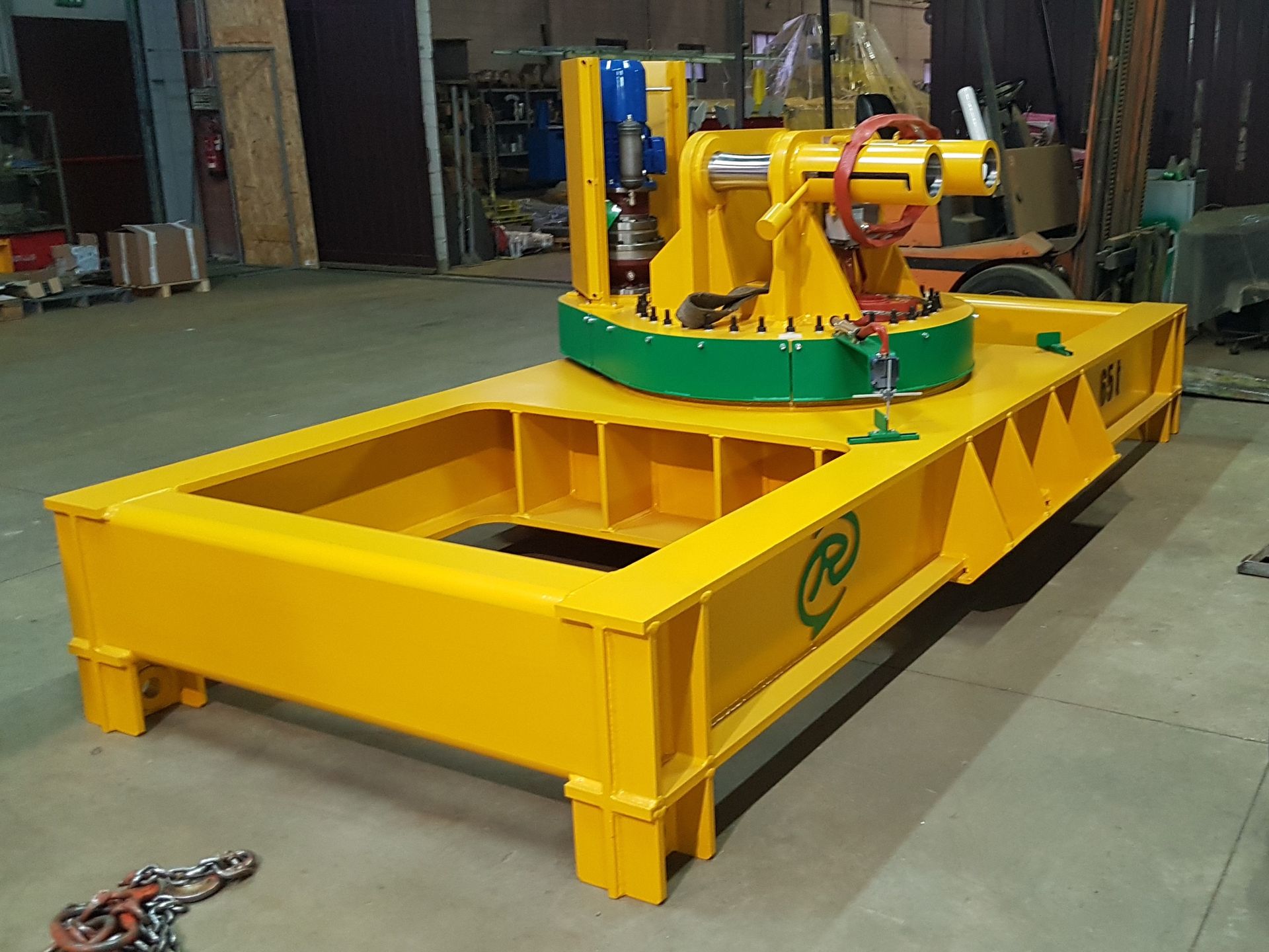 Macchina industriale gialla con un componente centrale rotante su una piattaforma gialla. Dettagli verdi e rossi.
