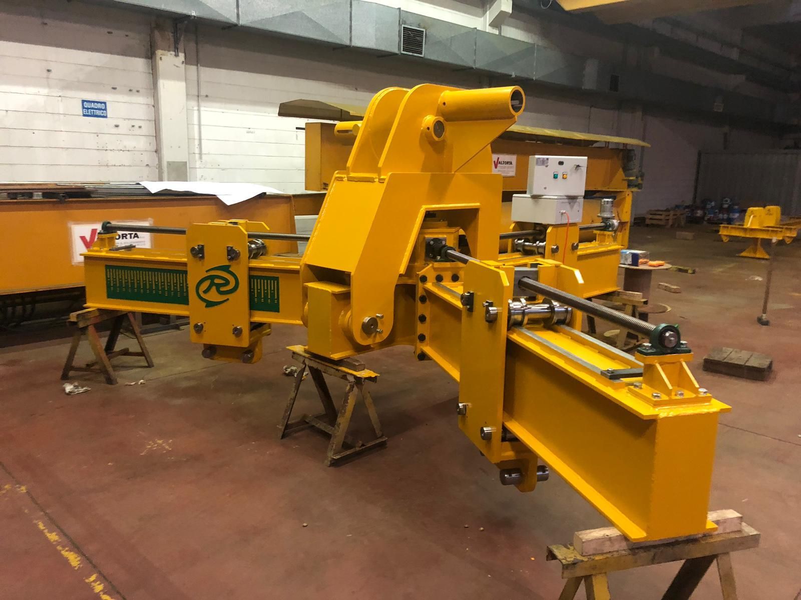 Componente giallo di macchinari industriali su supporti in una fabbrica.