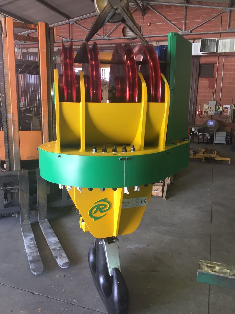 Componente giallo e verde della gru appeso a un paranco. Sono visibili le pulegge rosse.