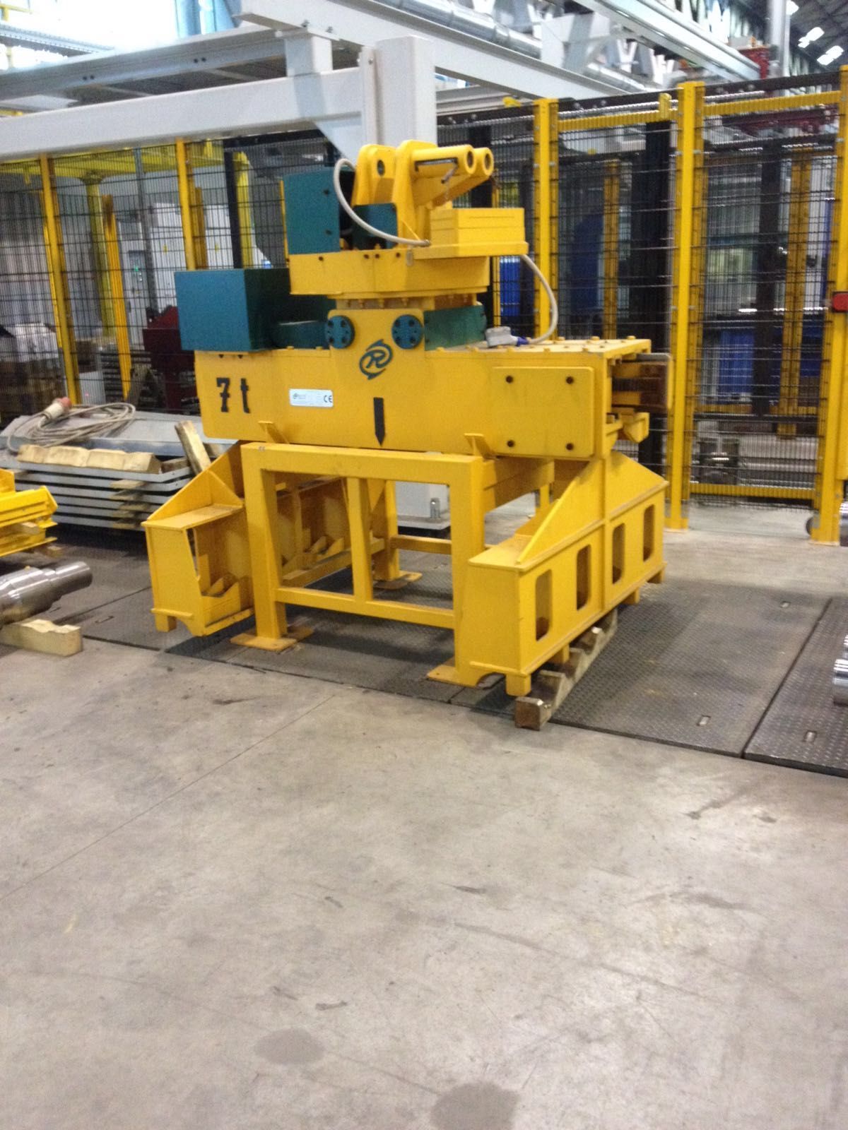 Macchina robotica industriale gialla, probabilmente una gru, in un ambiente di fabbrica, appoggiata su un pallet.