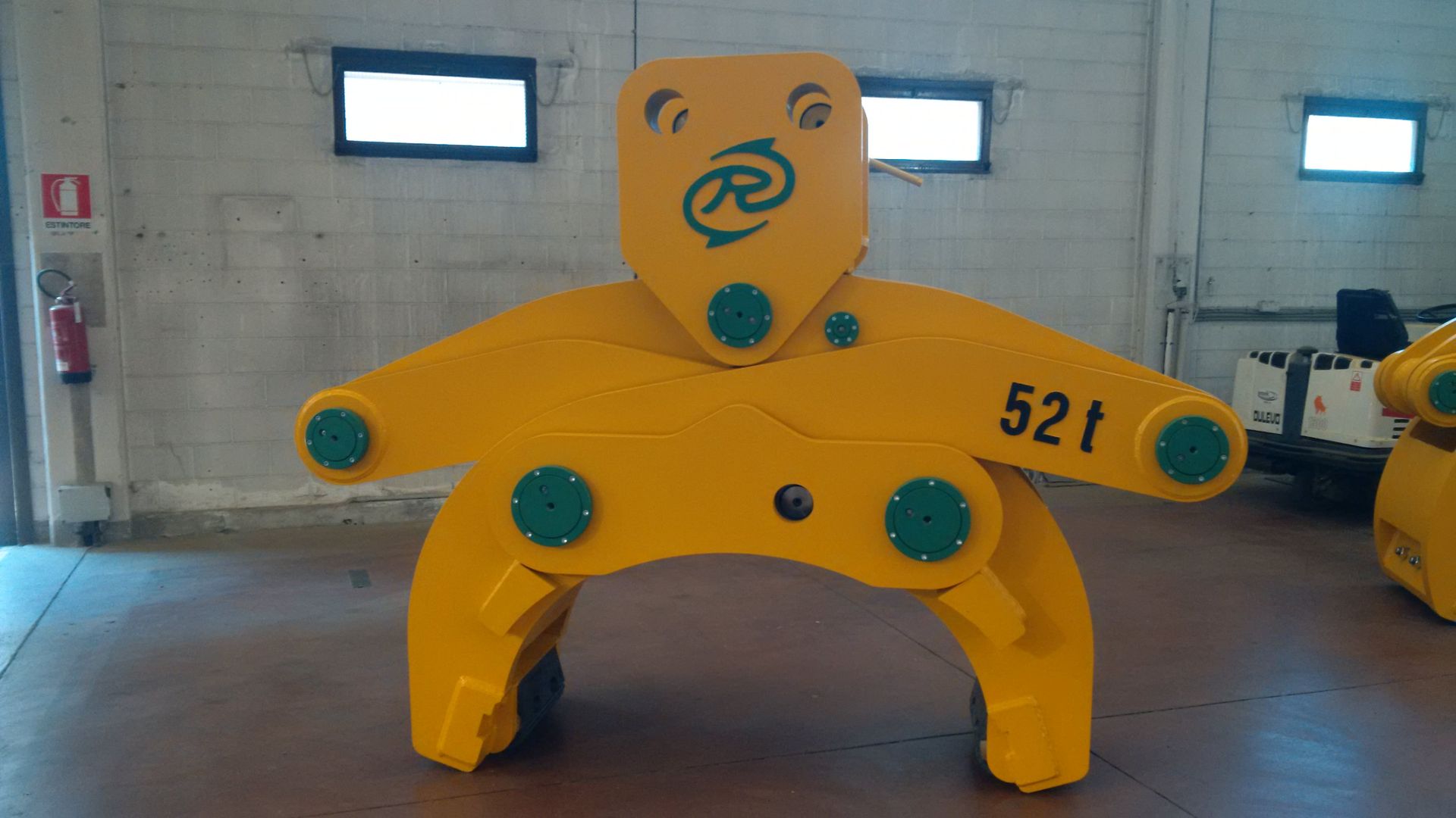 Pinza di sollevamento industriale gialla, capacità 52 tonnellate, all'interno di un magazzino.