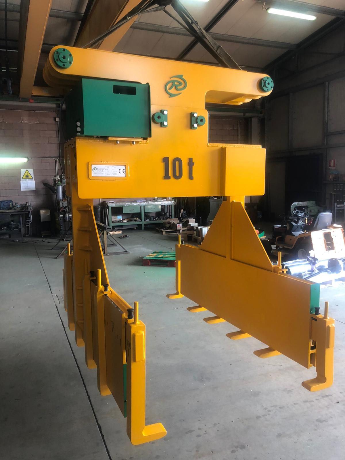 Pinza di sollevamento industriale gialla e verde da 10 tonnellate appesa alla gru a ponte.