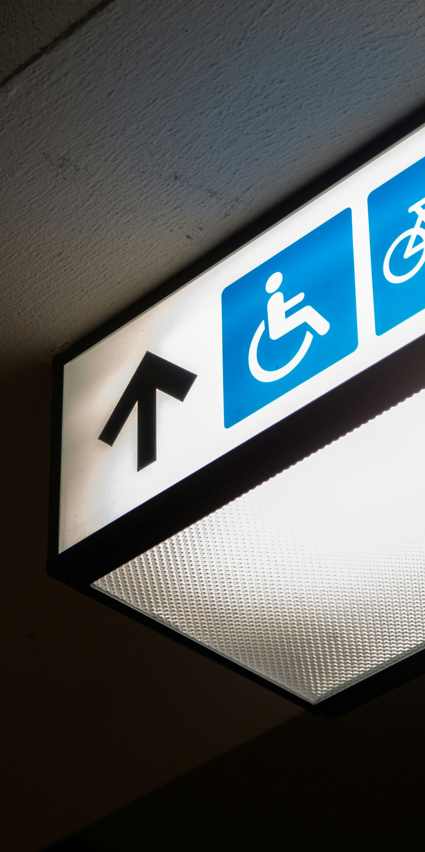 Panneau lumineux avec flèche vers le haut, symbole de fauteuil roulant et symbole de vélo. Obligations PMR