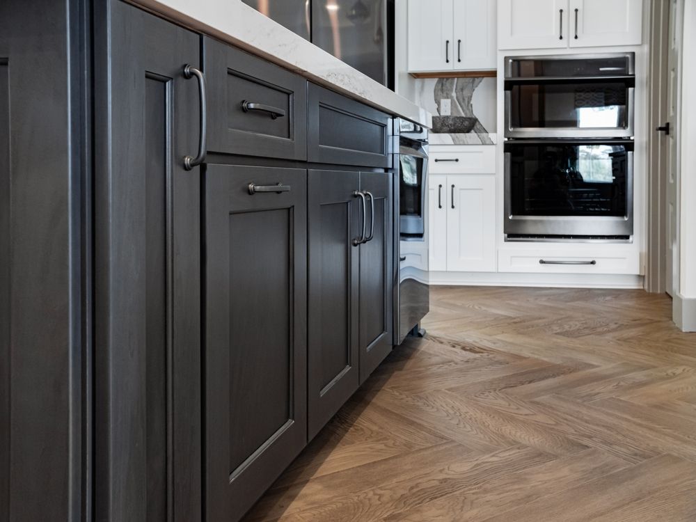 A kitchen with gray cabinets , white cabinets and stainless steel appliances.