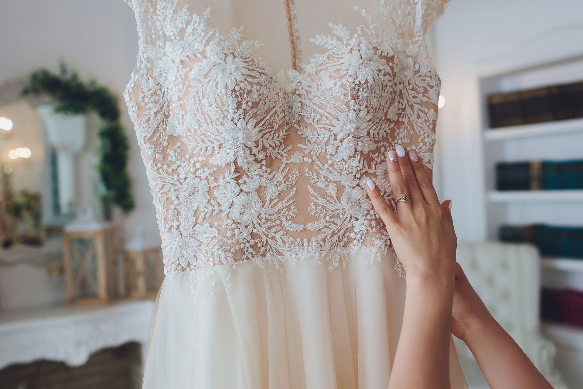 Rich pink wedding dress hangs on a chandelier in a white room