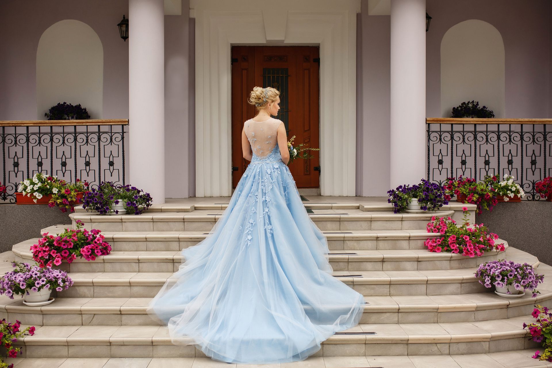 Wedding. Bride in blue wedding dress on stairs with flowers