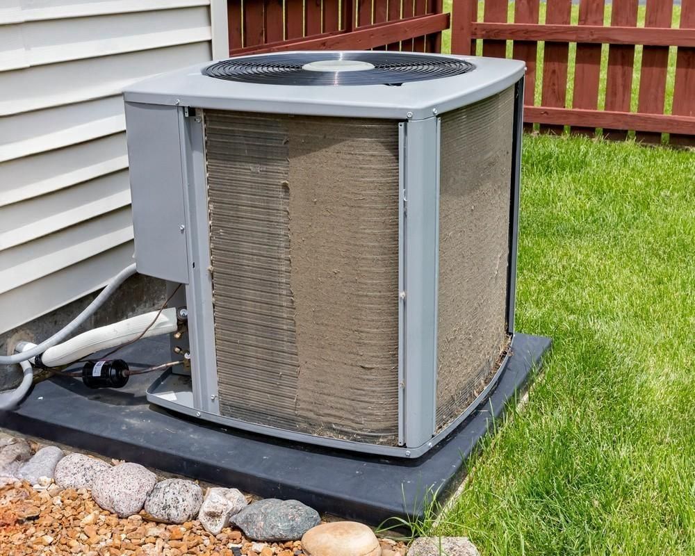 An air conditioner is sitting on the side of a house.