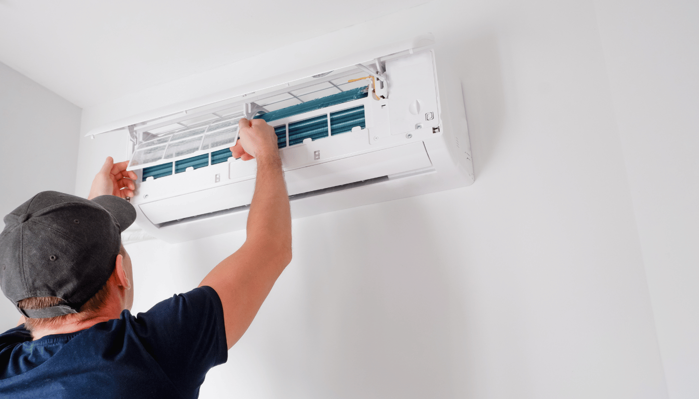 A man is installing an air conditioner on a wall.