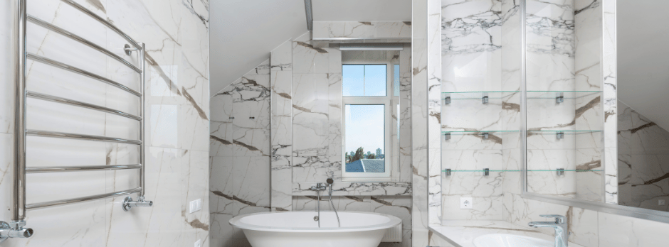 A bathroom with marble tiles , a tub , a sink and a window.