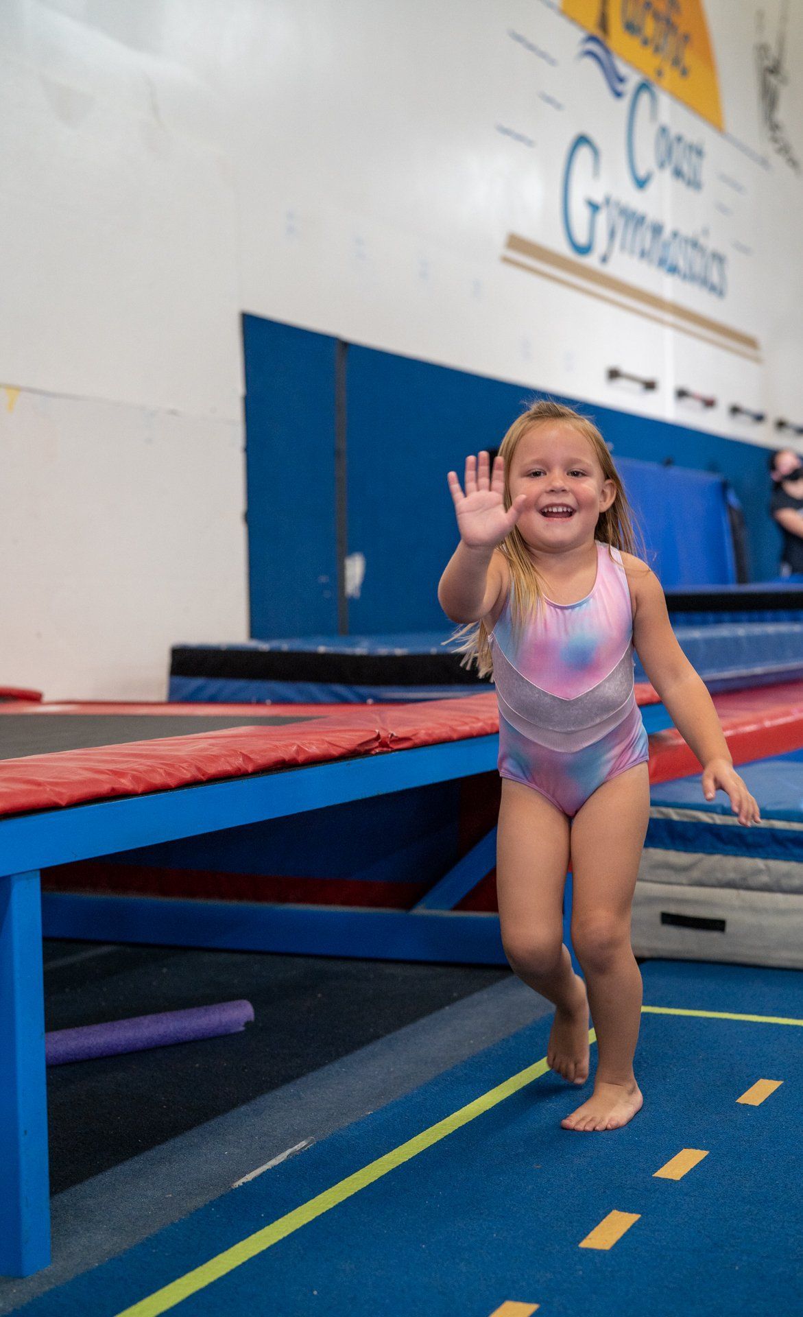 A little girl is walking on a balance beam in a gym.