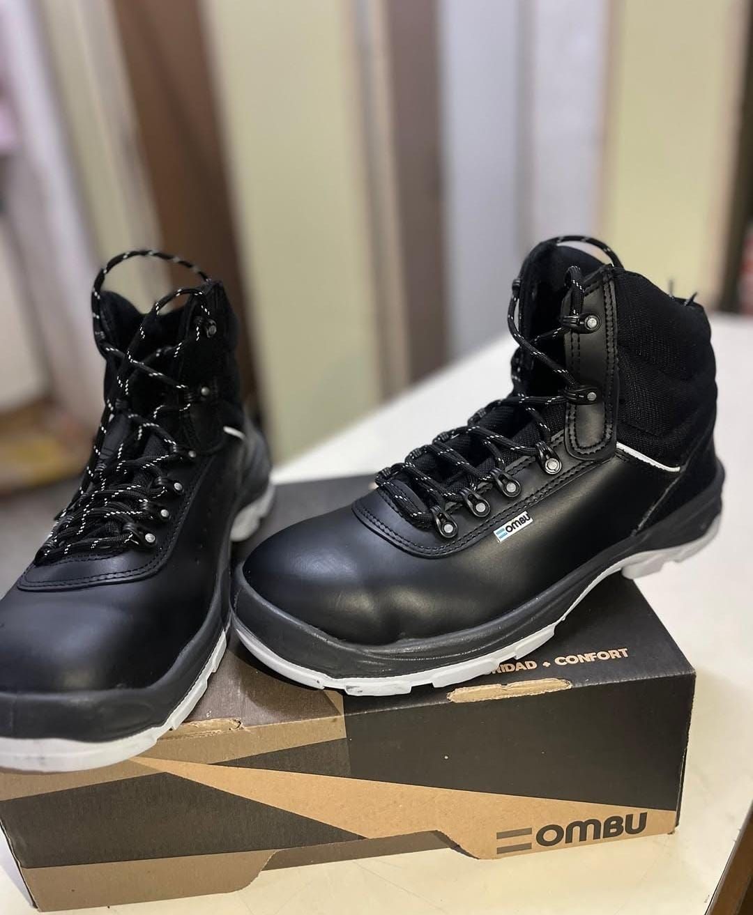 Un par de botas negras de caña alta sobre una caja de zapatos en el interior.