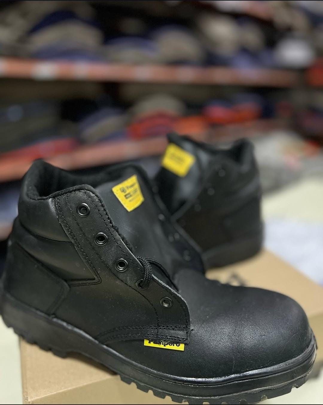 Botas de trabajo negras con etiquetas amarillas expuestas en un estante.