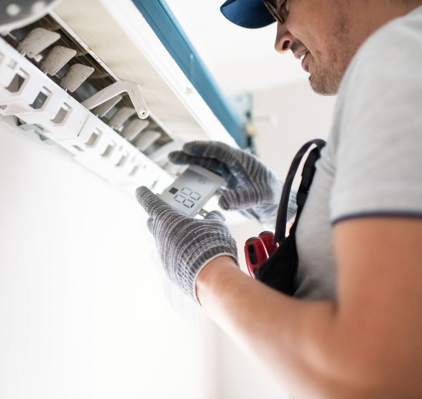 Technician wearing a uniform and gloves performing an air conditioning repair in a residential home. — Nashville, TN — Hermitage Heating & Air Conditioning