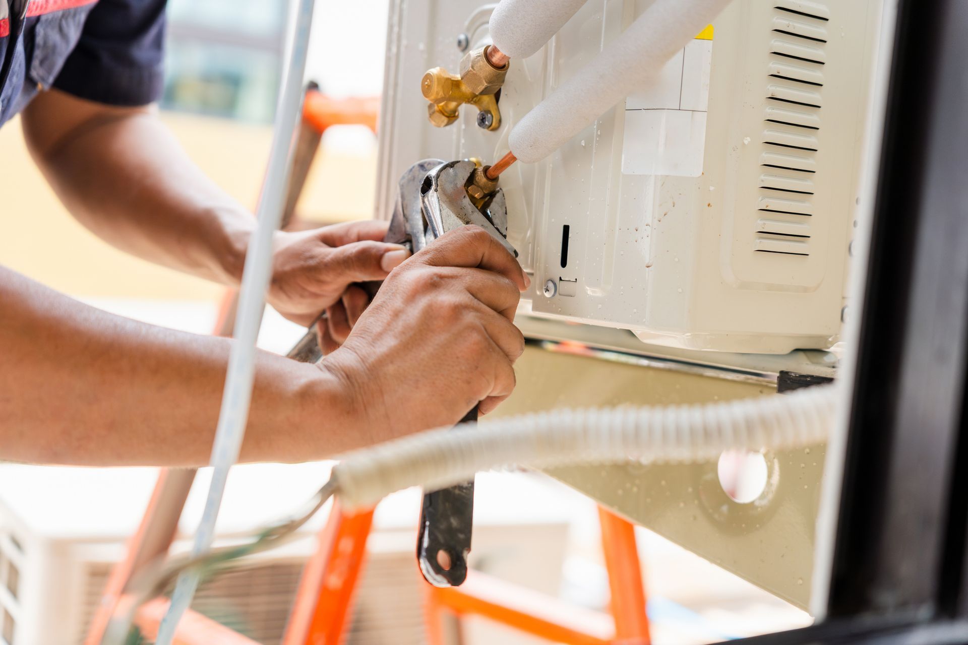 HVAC technician repairing AC unit with wrench – close-up of hands, tools, and cooling equipment.