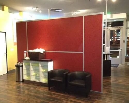 A waiting room with two chairs and a red wall.