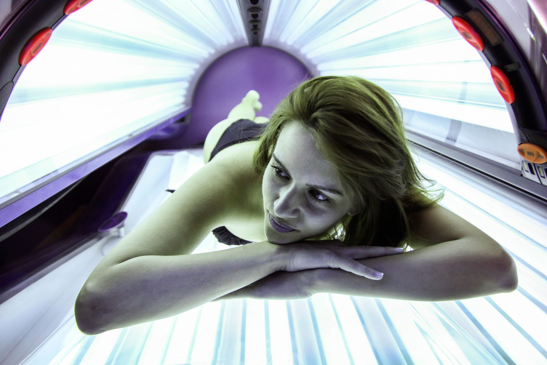 A woman is laying in a tanning bed.