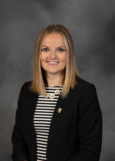 A woman in a black jacket and striped shirt is posing for a picture.
