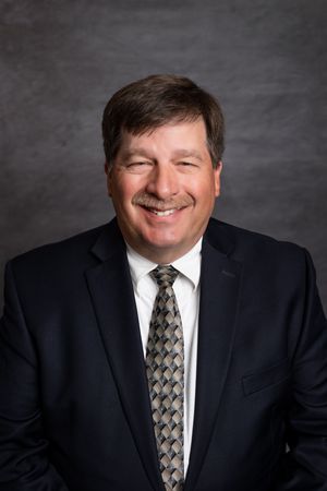 A man in a suit and tie is smiling for the camera.