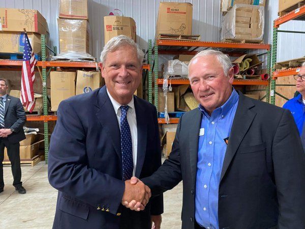 Two men in suits shaking hands in a warehouse