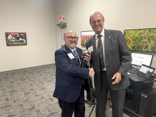 Two men in suits are shaking hands in a room.