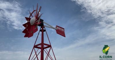 A red and white windmill is against a blue sky.