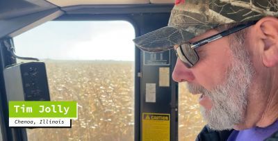 A man with a beard is driving a tractor in a field.